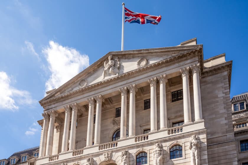 Bank of England. The photo is from the ground and looks up. The flag is blown by the wind and there are clouds in background.