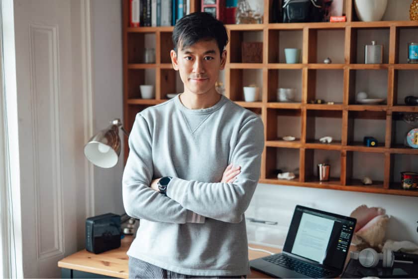 Confident asian man looking at the camera, his arms are crossed and he's smiling.