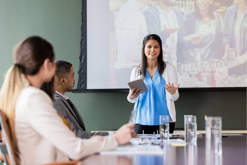 charity_event_presentation Confident business woman doing a presentation in front of her peers. Her peers are invested. The presenter is focused and her slides are presenting details for an upcoming charity event.