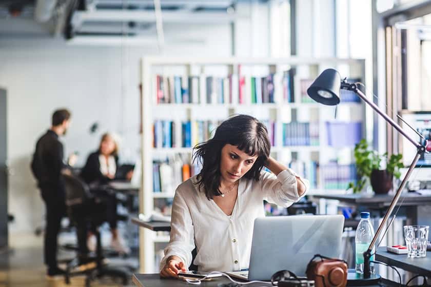 A woman sits in an office looking worried.