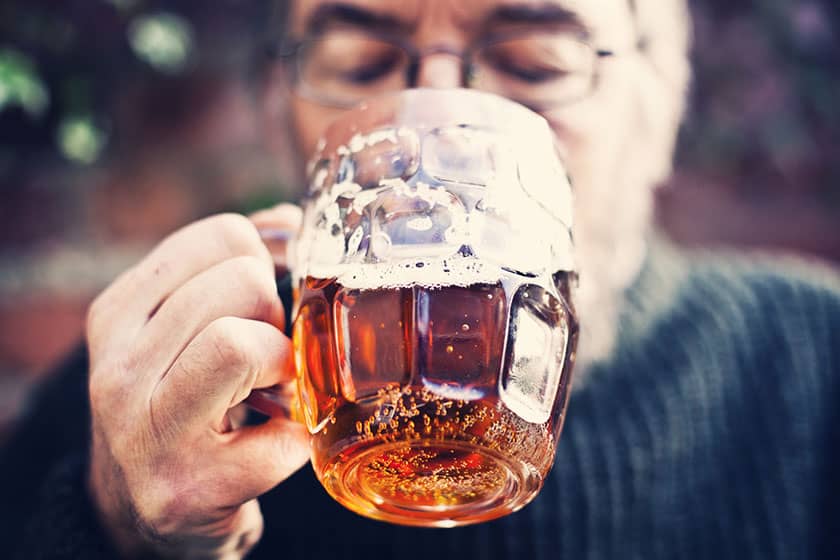 Man drinks real ale from a handled pint glass.