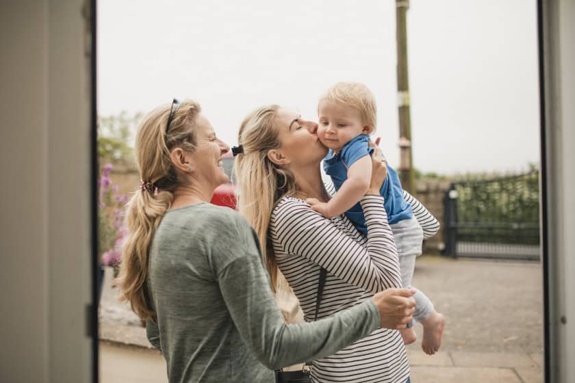 happy_family_raising_their_child_to_the_sky Mother kissing son on the cheek.