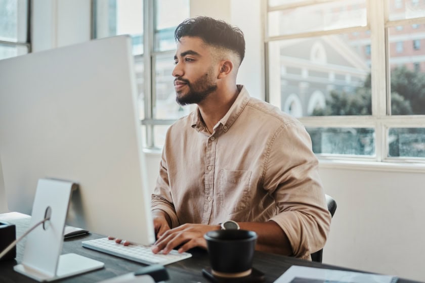 man leaning into computer, he's very focused on his work.
