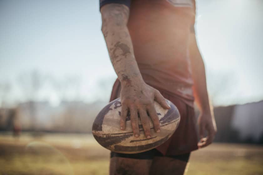 rugby Rugby player holding ball on field