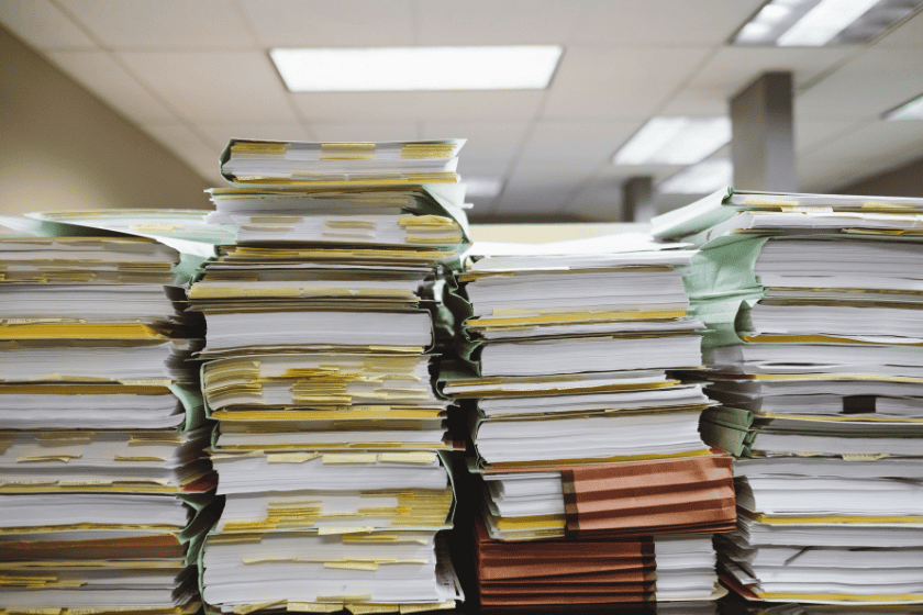 Stacks of folders and books with sticky note tabs on a table