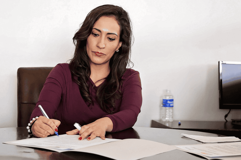 A business professional writes on a piece of paper in an office