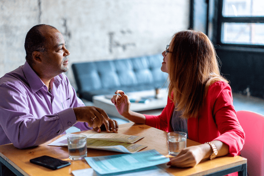 A tax agent advises a client sitting down at a table