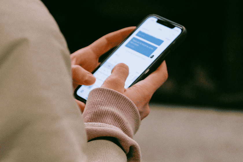 A person holds a phone with a chat bot messaging platform open on their screen.
